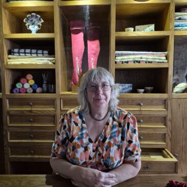 Gladstone's land middle floor set up as a drapers shop with lady behind the counter