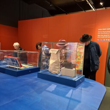 three women and a man study museum exhibit